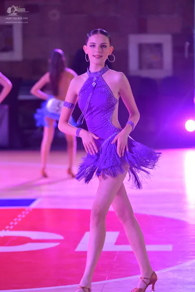 Dancesport competitor: Female dancer (foreground): purple Latin dance dress with a halter neckline, emb