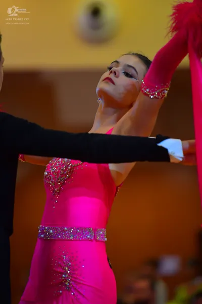 Dancesport competitor: Female dancer: bright pink latin dress with rhinestone embellishments and a matc