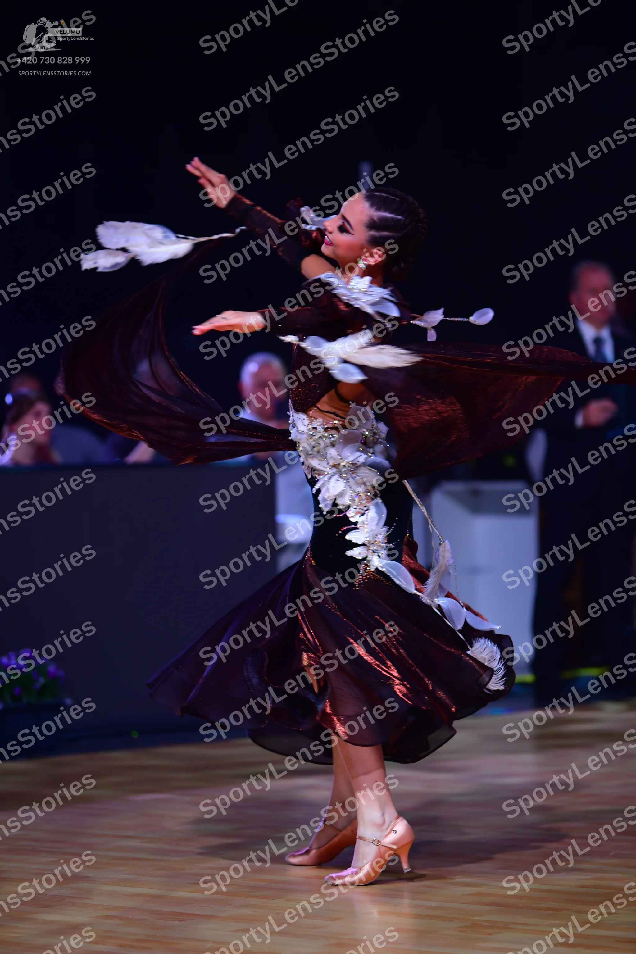 Dancesport competitor: Female dancer: deep burgundy long-sleeved ballroom dress with large white feathe