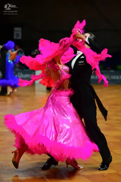 Dancesport competitor: Female dancer: bright pink ballroom dress with a voluminous skirt, shiny fabric,