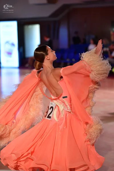 Dancesport competitor #92: Female dancer: peach ballroom gown with voluminous feather trim on the sleeves a