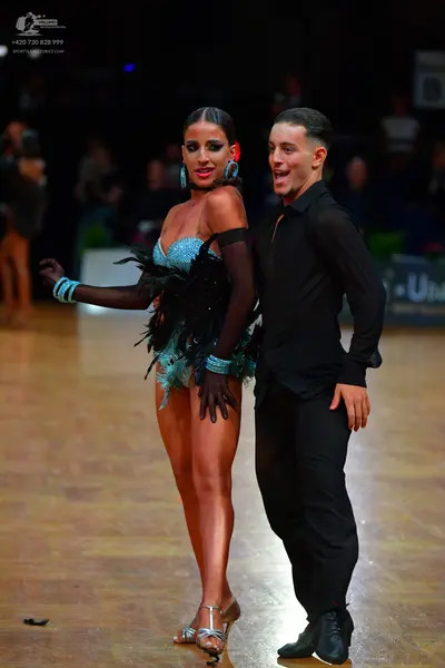 Dancesport competitor: Female dancer: teal sequined latin costume with black feather detailing and matc