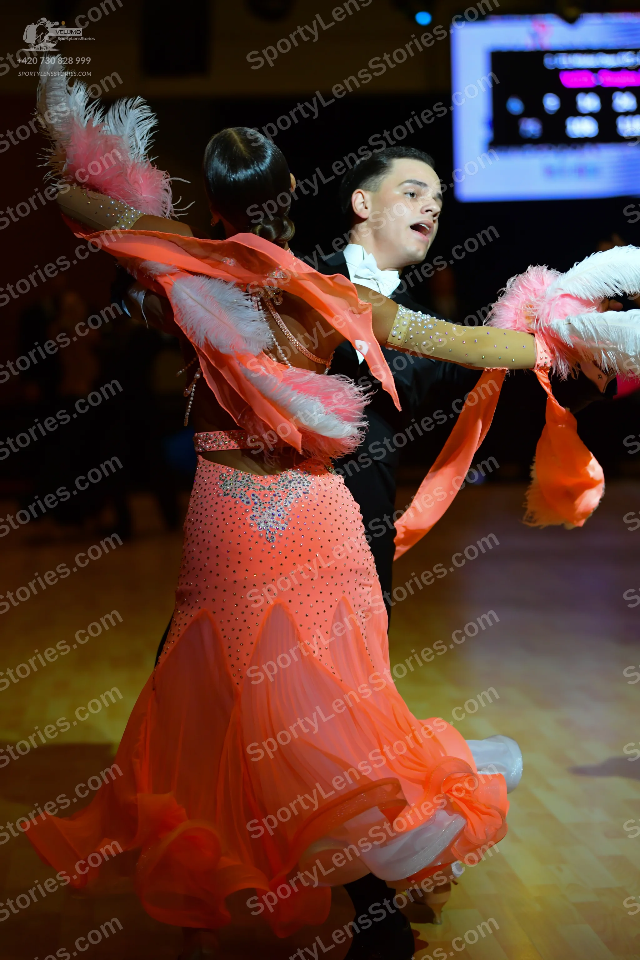 Dancesport competitor: Female dancer: coral-colored ballroom dress with a flowing, multi-layered skirt 