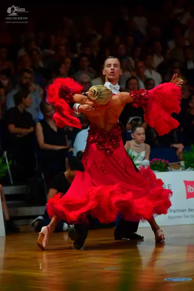 Dancesport competitor: Female dancer: bright red Latin dance dress with a sequined bodice and voluminou