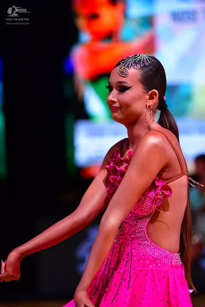 Dancesport competitor: Female dancer: bright pink Latin dress with rhinestones/sequins, thin straps, an