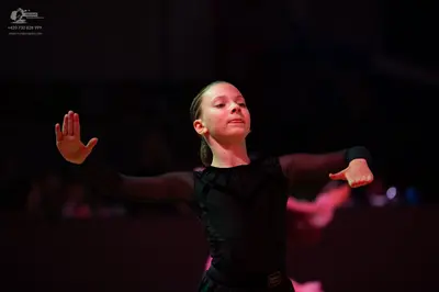 Dancesport competitor: Female dancer: black long-sleeved dance costume with sheer mesh sleeves