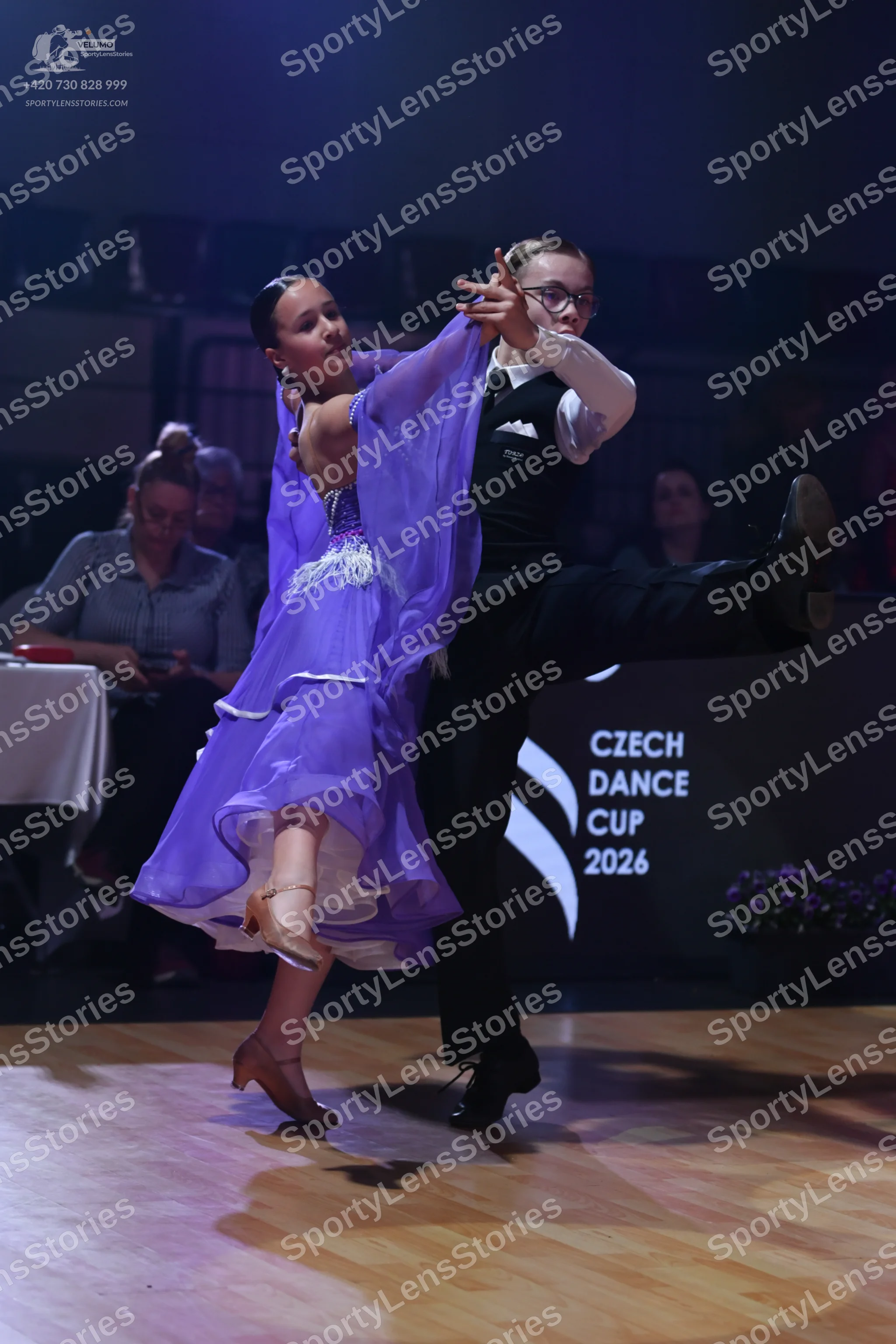 Dancesport competitor: Female dancer: purple ballroom dress with a sheer, flowing skirt and sleeves, an
