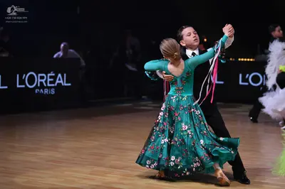 Dancesport competitor: Female dancer: teal long-sleeved ballroom gown with a floral pattern