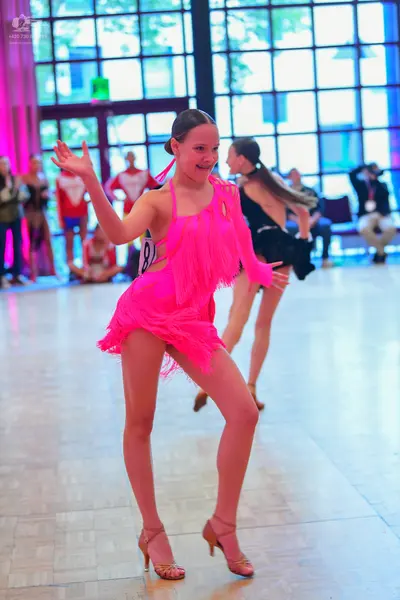 Dancesport competitor: Female dancer: bright pink Latin dress with long fringe