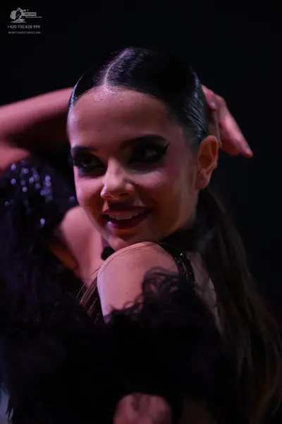 Dancesport competitor: Female dancer: black latin dress with textured, feathered embellishments