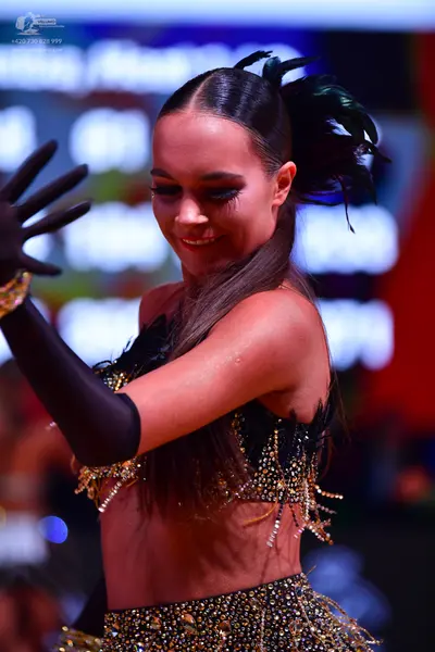 Dancesport competitor: Female dancer: black two-piece Latin costume with gold/yellow sequin and crystal