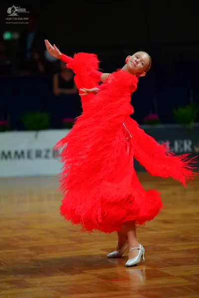 Dancesport competitor: Female dancer: red latin dress with voluminous fringe on the skirt and long slee