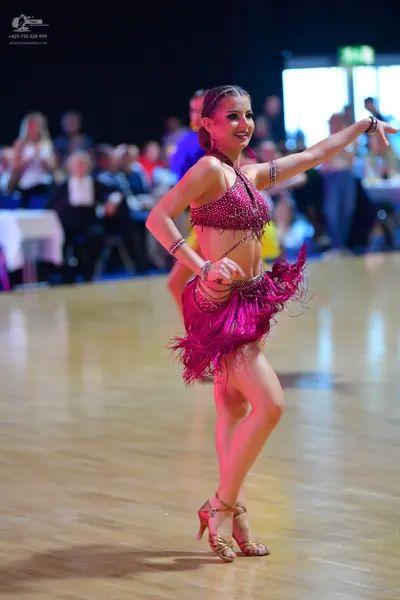 Dancesport competitor: Female dancer: magenta Latin dance costume with sequin embellishments and a frin