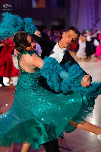 Dancesport competitor: Female dancer: teal sequined ballroom dress with large teal feathered or fringe-