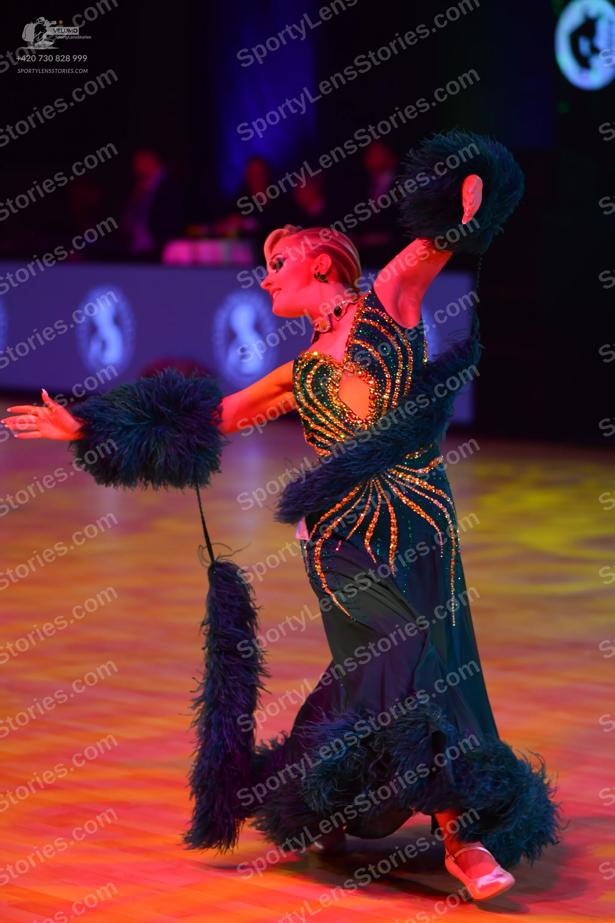 Dancesport competitor: Female dancer: dark green ballroom dress with gold sequin patterns, featuring la