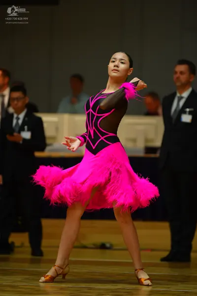 Dancesport competitor: Female dancer: bright pink and black Latin dance dress with a black patterned bo