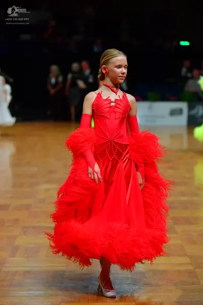 Dancesport competitor: Female dancer: bright red ballroom dance dress with a voluminous, feathery skirt