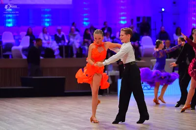 Dancesport competitor: Female dancer (foreground): orange latin dress with ruffles