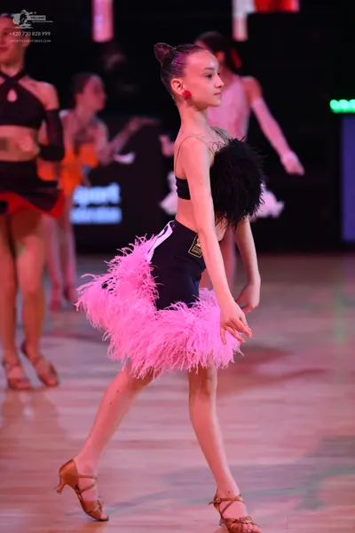Dancesport competitor: Female dancer in foreground: black two-piece latin costume with pink feather ski