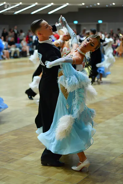 Dancesport competitor: Male dancer: black long-sleeved top with a white design on the shoulder and blac