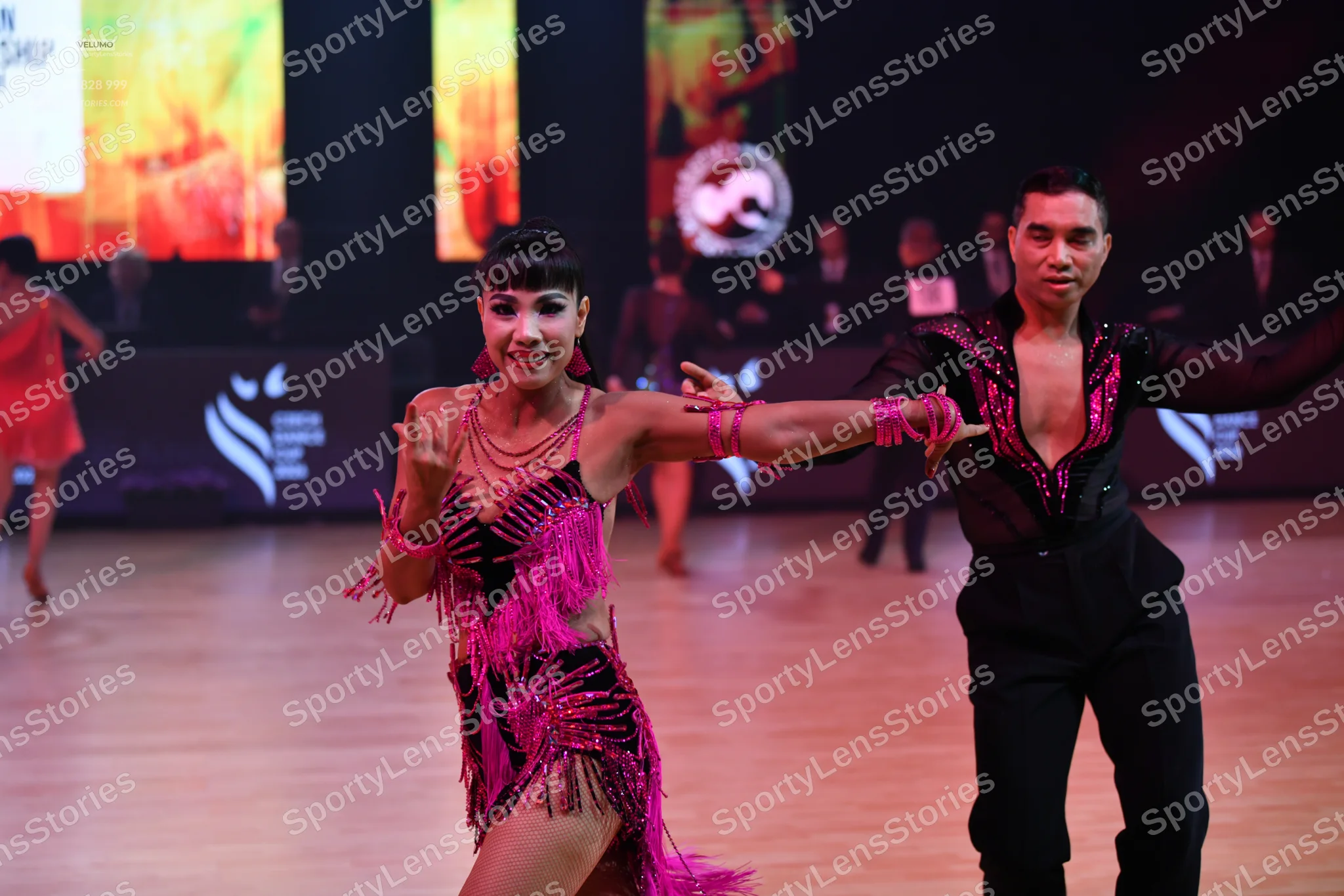 Dancesport competitor: Male dancer: black long-sleeved shirt with pink sequin patterns and black trouse