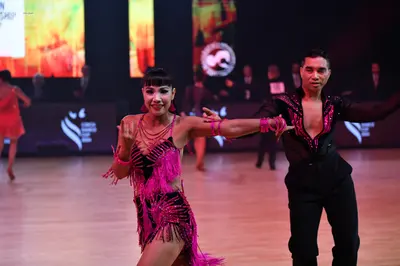 Dancesport competitor: Male dancer: black long-sleeved shirt with pink sequin patterns and black trouse