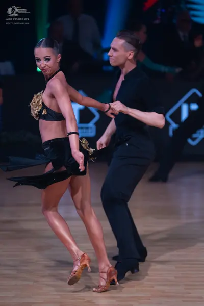 Dancesport competitor: Female dancer: black two-piece Latin costume with a bra top and skirt featuring 