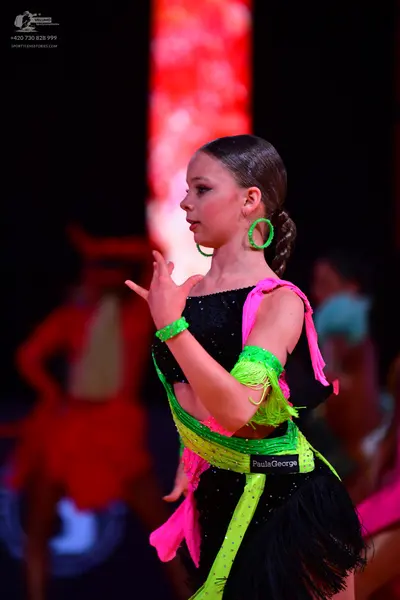 Dancesport competitor: Female dancer: black latin dress with neon green sequins, neon green fringe, and