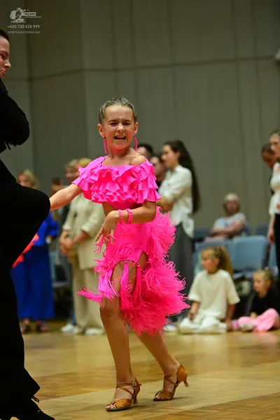 Dancesport competitor: Female dancer: bright pink Latin dress with layered, fringed-style fabric