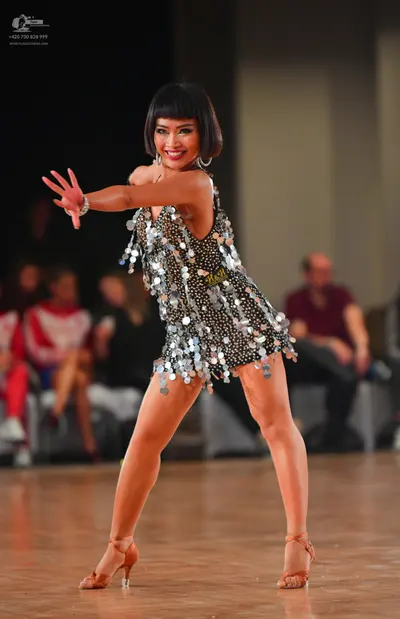 Dancesport competitor: Female dancer: dark latin dress heavily embellished with large, silver, shiny se