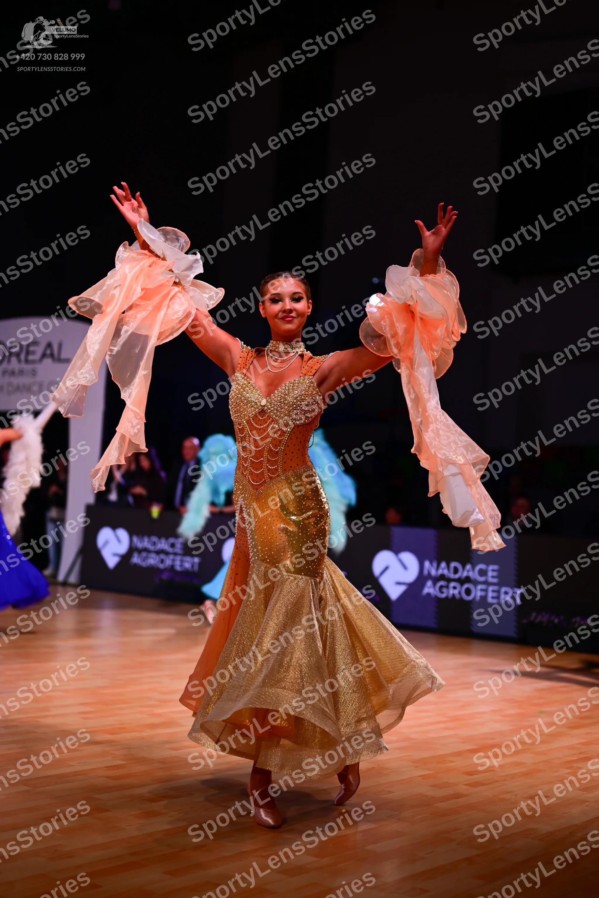 Dancesport competitor: Female dancer: gold ballroom gown with a shimmering, sequined bodice and skirt,