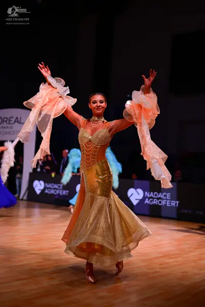 Dancesport competitor: Female dancer: gold ballroom gown with a shimmering, sequined bodice and skirt, 