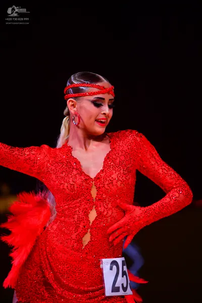 Dancesport competitor: Female dancer: red latin dress with long sleeves, covered in red sequins, and re