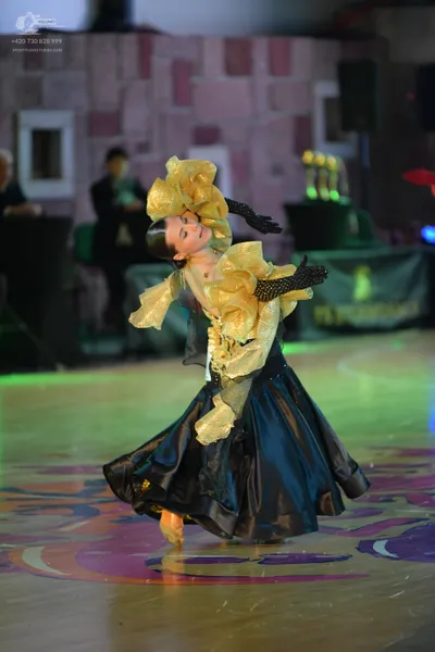 Dancesport competitor: Female dancer: gold metallic ruffles and bodice with a large, voluminous black s