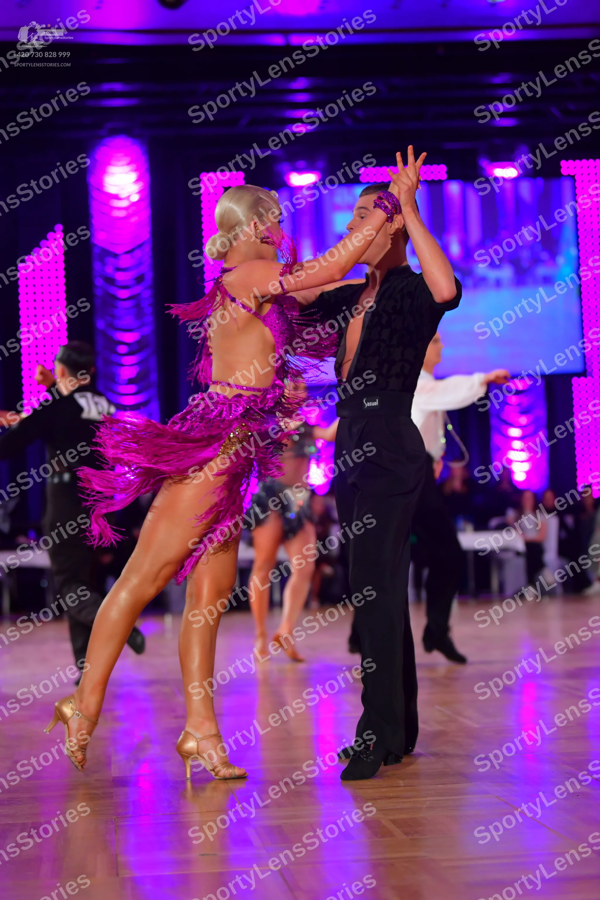 Dancesport competitor: Female dancer: magenta/purple Latin dress with long fringe and gold sequin embel