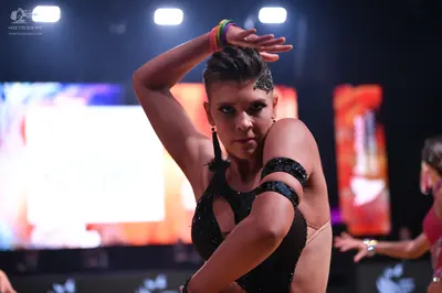Dancesport competitor: Female dancer in foreground: black latin dress with small sequins and black band