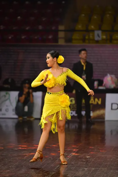 Dancesport competitor: Female dancer: yellow Latin dress with long sleeves and yellow fringe