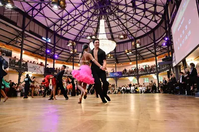 Dancesport competitor: Main female dancer: pink/magenta Latin dress with a flared skirt and a nude-colo