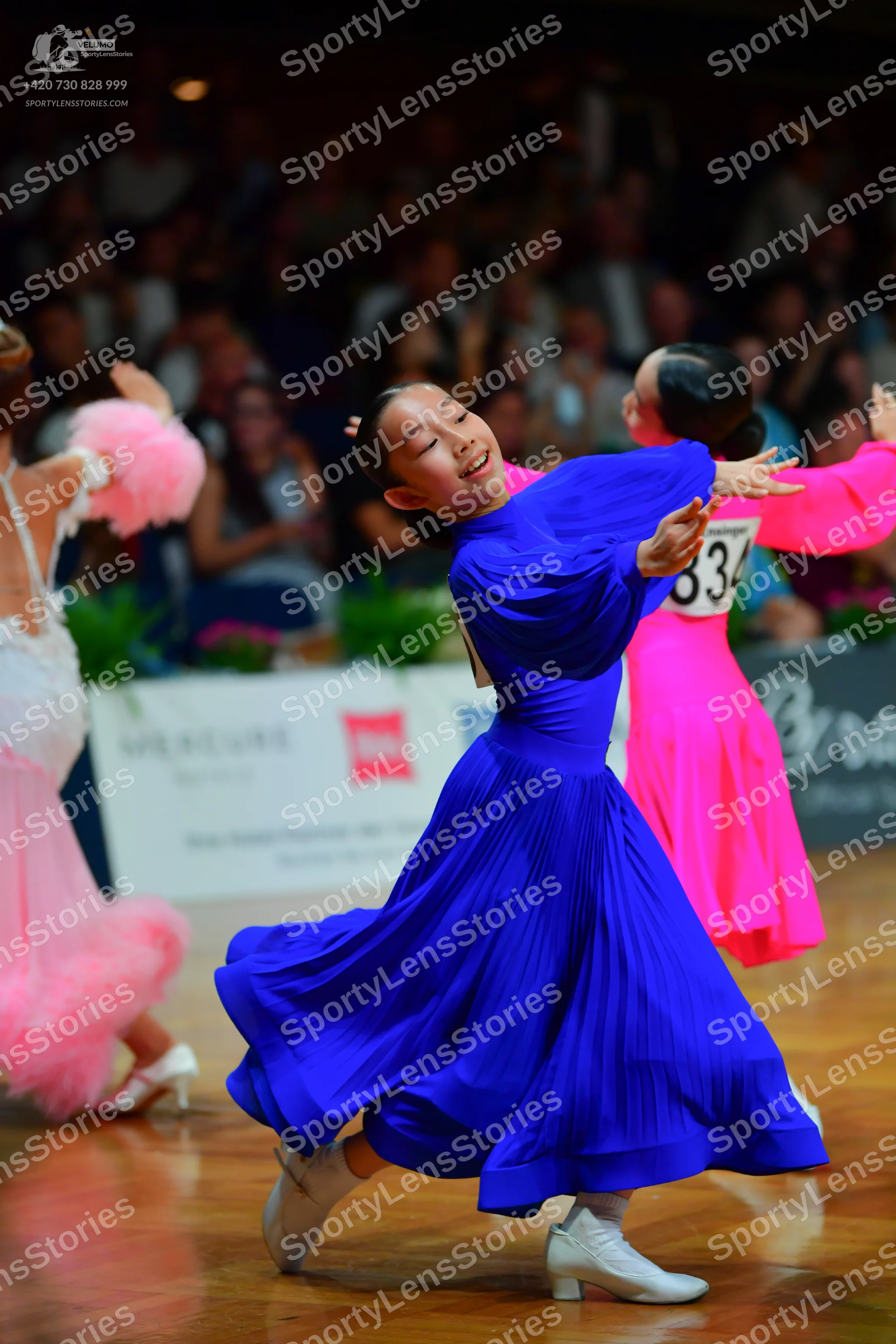 Dancesport competitor: Female dancer in blue: royal blue ballroom dress with long sleeves and a large,