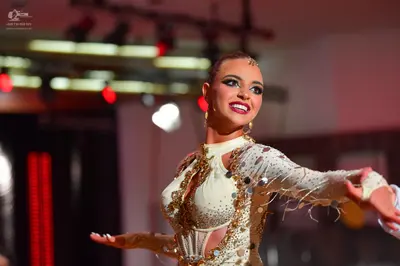 Dancesport competitor: Female dancer: cream-colored Latin dance dress heavily embellished with sequins 