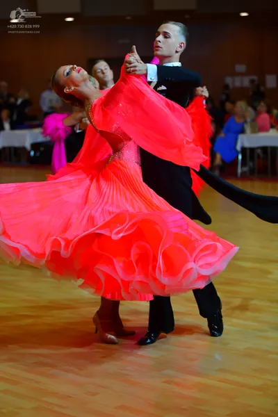 Dancesport competitor: Female dancer: bright pink ballroom dress with a voluminous, ruffled chiffon ski