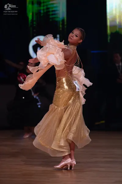 Dancesport competitor: Female dancer: gold sequined and glittery ballroom dress with large, voluminous 