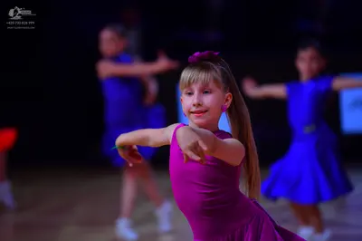 Dancesport competitor: Female dancer in foreground: bright magenta sleeveless dress made of smooth, str