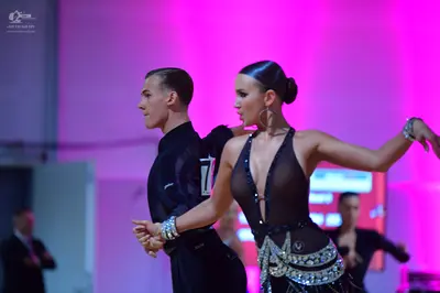 Dancesport competitor: Male dancer: black long-sleeved shirt, black trousers, and a sparkling silver cu