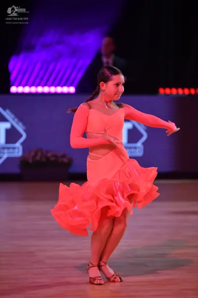 Dancesport competitor: Female dancer: peach-colored Latin dress with sheer long sleeves and a voluminou