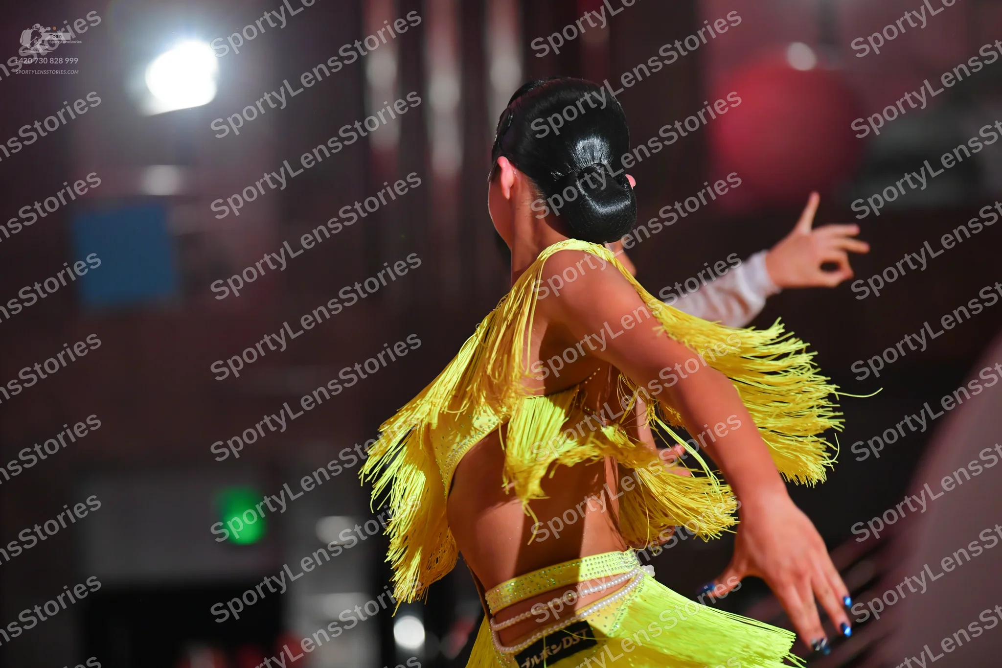 Dancesport competitor: Female dancer: bright yellow Latin dance costume featuring extensive long fringe