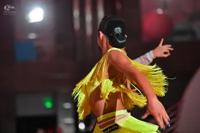 Dancesport competitor: Female dancer: bright yellow Latin dance costume featuring extensive long fringe