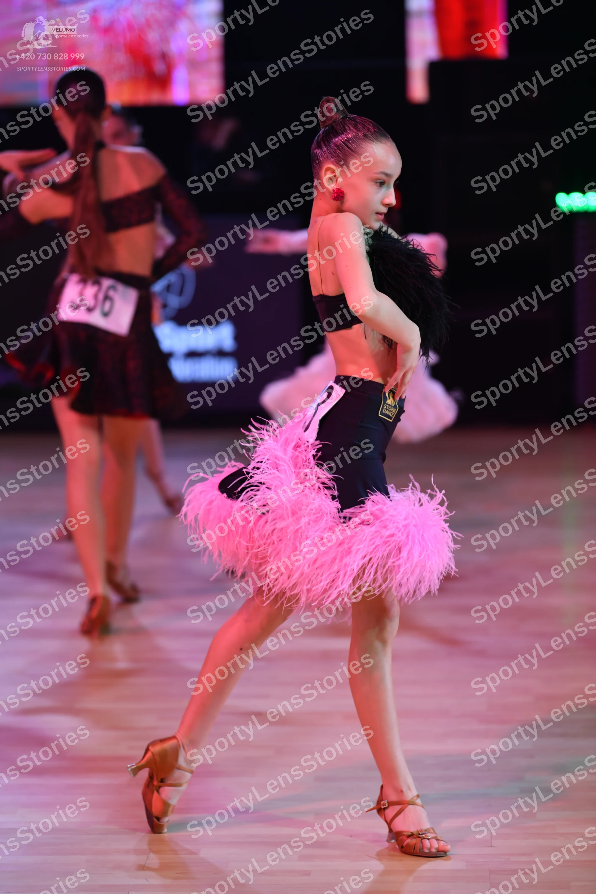 Dancesport competitor: Female dancer (left): dark maroon long-sleeved Latin dance costume with a backle