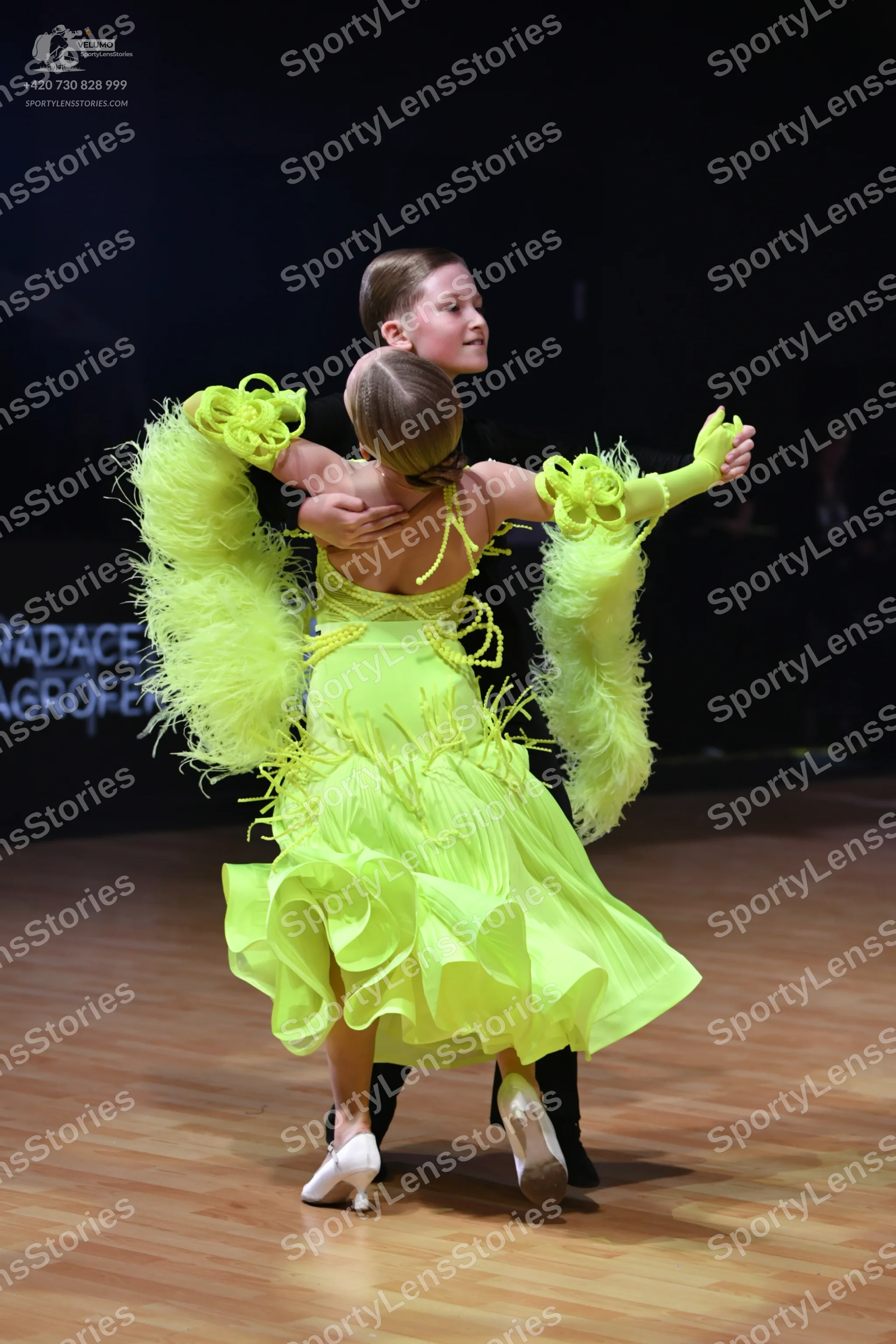 Dancesport competitor: Female dancer: lime green Latin dance dress with voluminous feathered/fringed sl