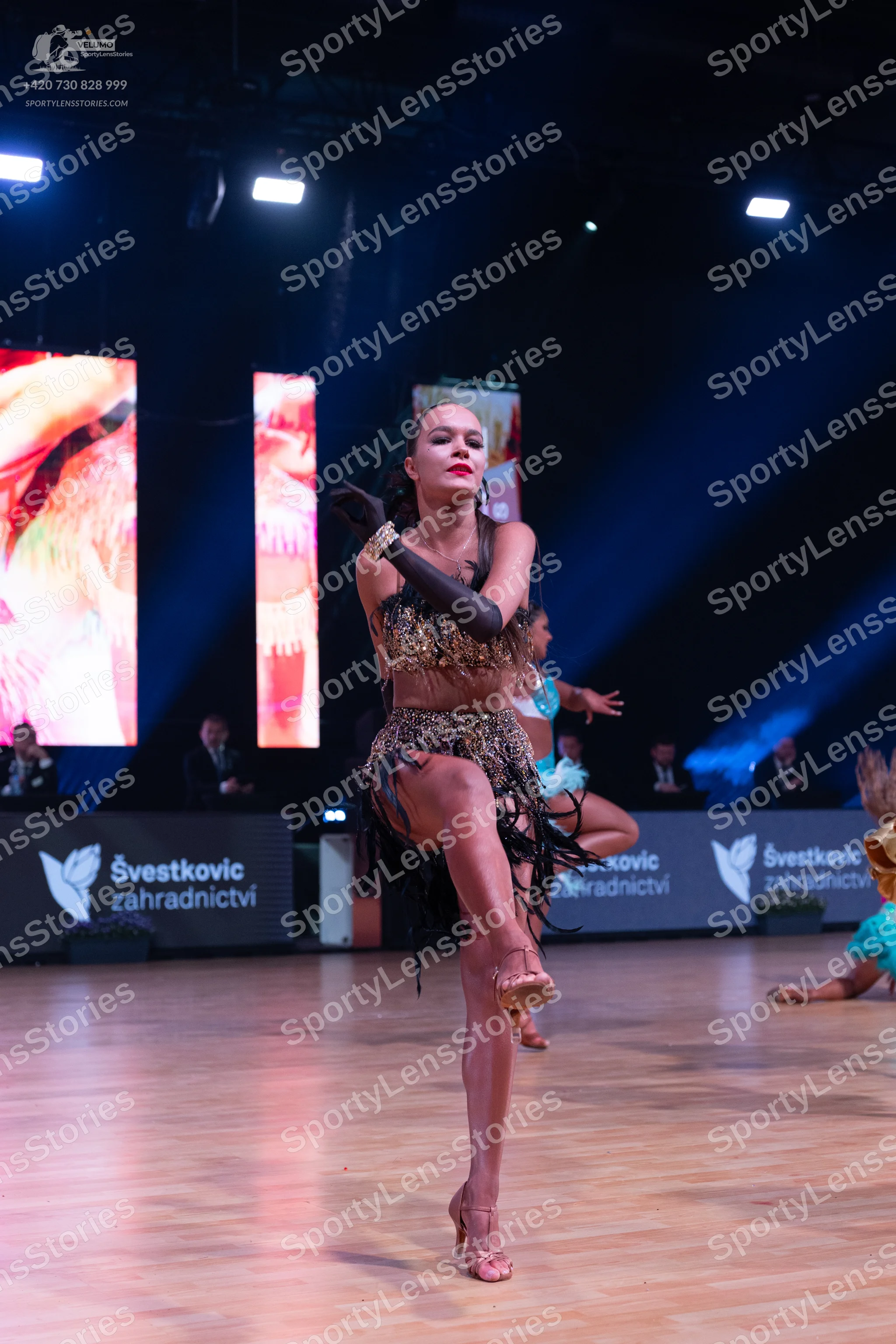 Dancesport competitor: Female dancer in foreground: bronze-colored sequined Latin dress with a fringed